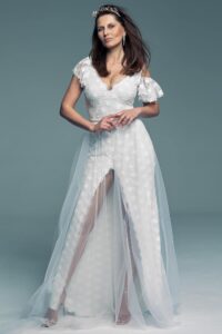 suknia ślubna z koronkowymi rękawami i tiulowym dołem, modelka stoi na neutralnym tle