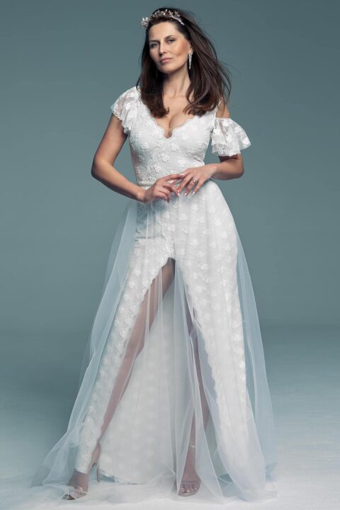 suknia ślubna z koronkowymi rękawami i tiulowym dołem, modelka stoi na neutralnym tle