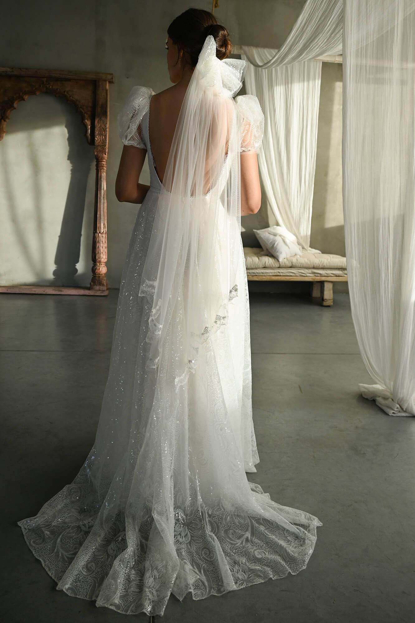 suknia ślubna z odkrytymi plecami i delikatnym materiałem, z koronkowymi detalami na dole.