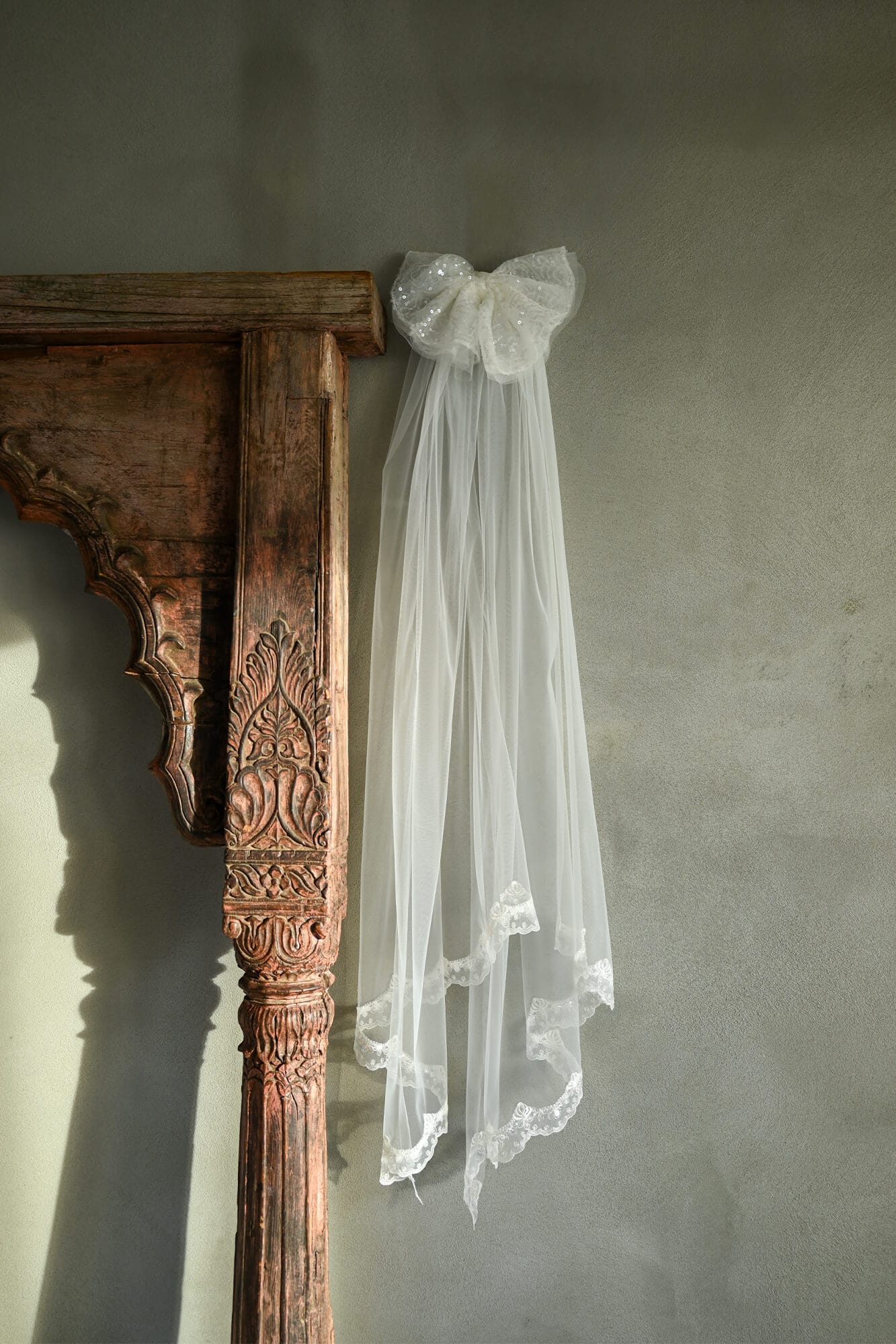 Welon w kolorze białym z kokardą, zawieszony na ozdobnym elemencie architektonicznym.