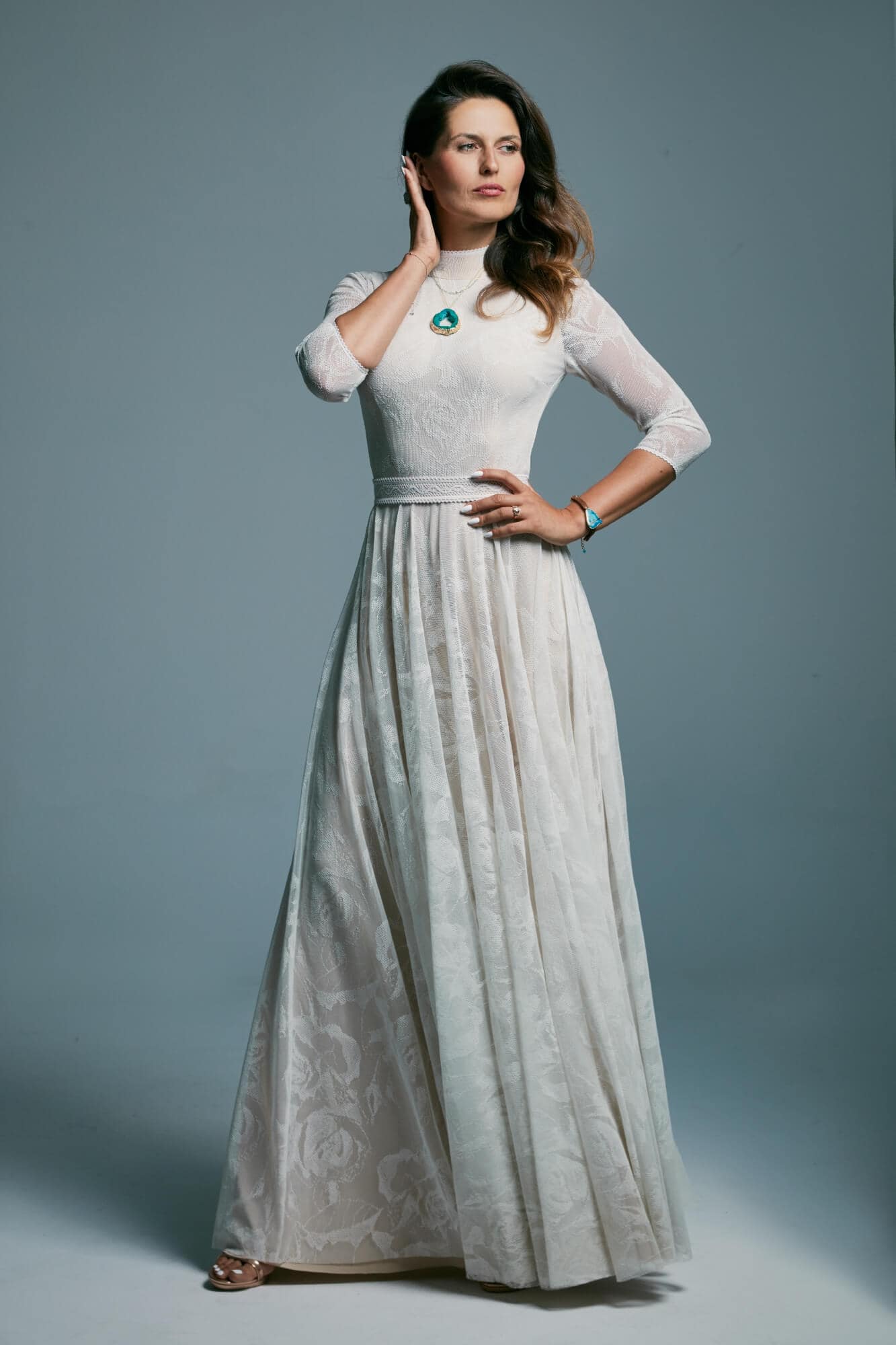 suknia ślubna z długim rękawem, w kolorze białym, z delikatnym wzorem na materiale.