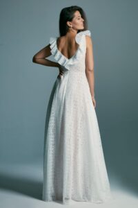 suknia ślubna z odkrytymi plecami i falbanami na ramionach, w kolorze białym.